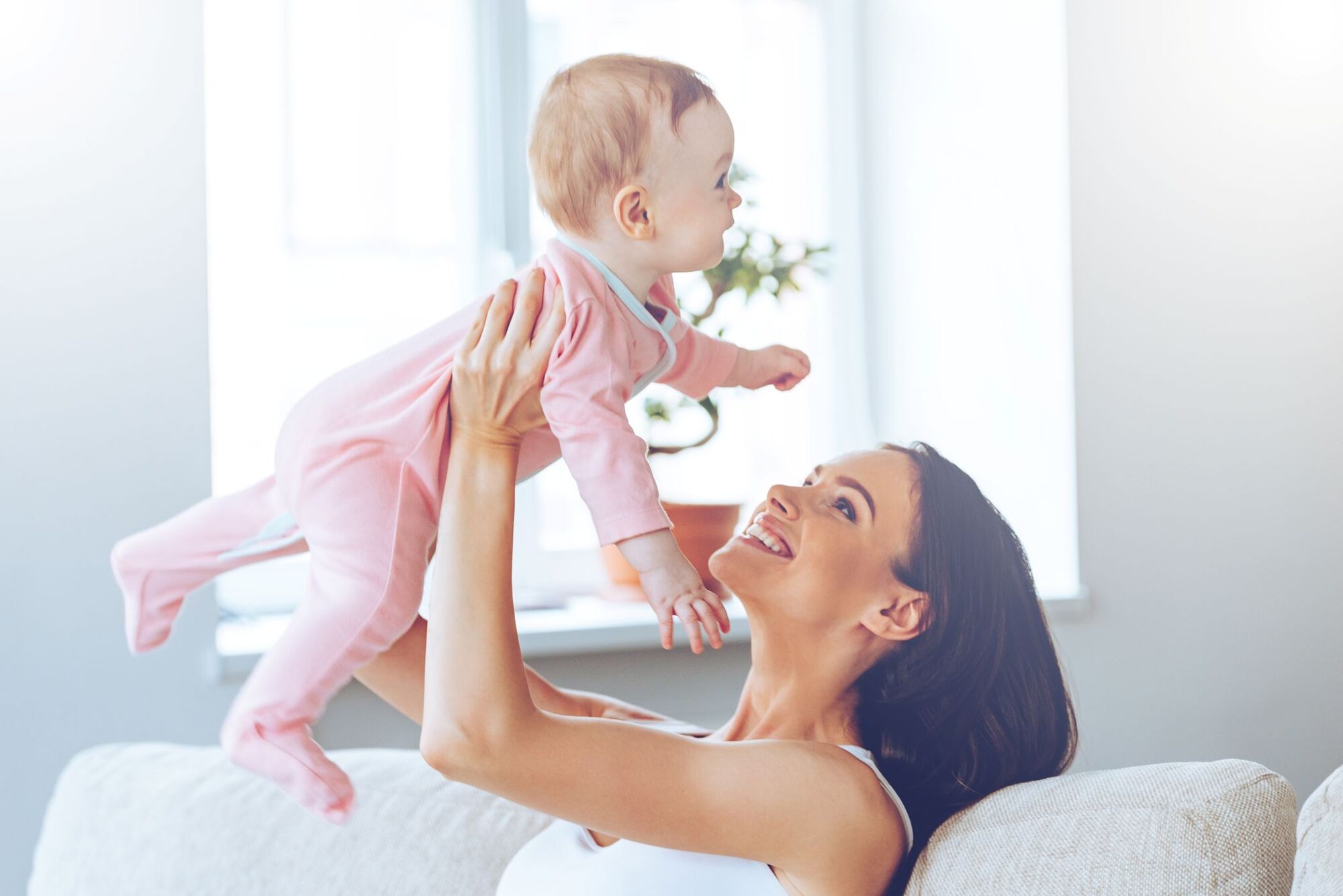 Young mother lifting baby in living room