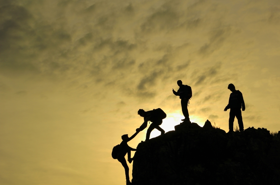 Close view of man at top of mountain looking down at sunset.