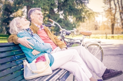 Retired couple sitting on a park bench after a bike ride.