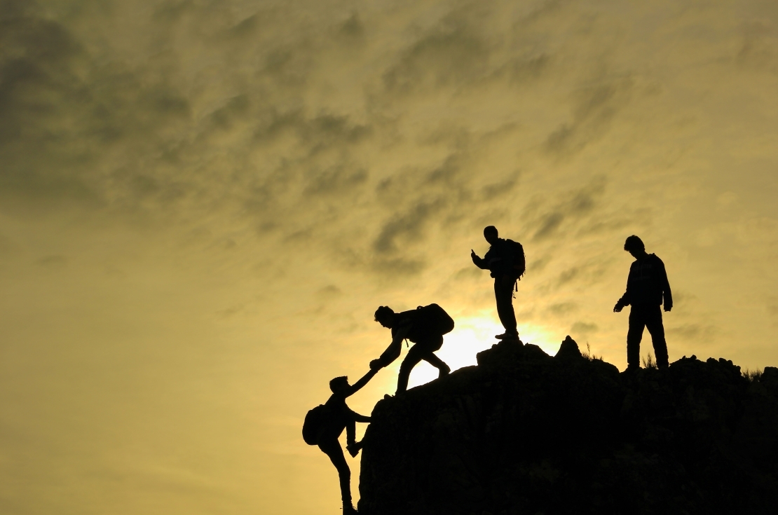 Close view of man at top of mountain looking down at sunset.