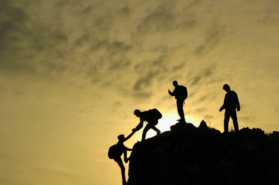 Close view of man at top of mountain looking down at sunset.