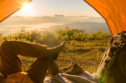 Man laying in tent looking out at mountains reflecting on the accomplishments of his Journey.