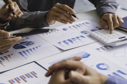 Retired couple with financial adivsor sitting at a desking signing paperwork.