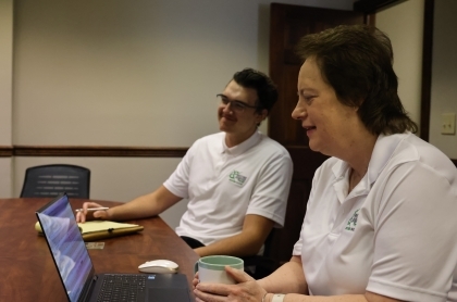 Retired couple with financial adivsor sitting at a desking signing paperwork.