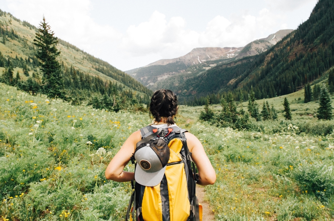 Woman hiking in the mountain with a yellow backpack.