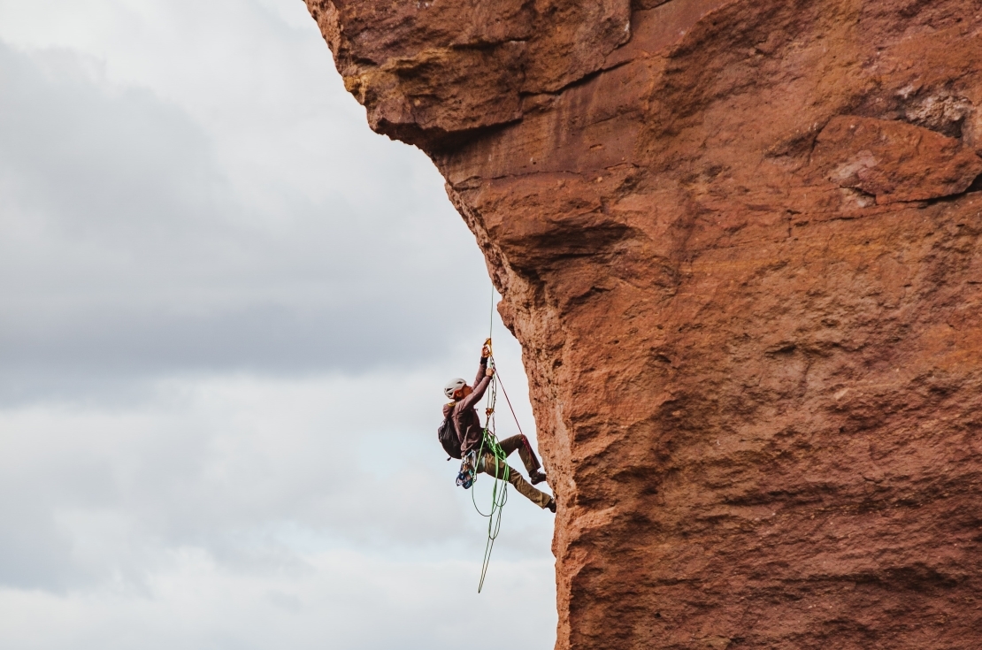 Man repelling down the side of a rock mountain. 