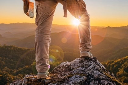 Close view of man at top of mountain looking down at sunset.