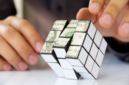 Man wearing a scarf and sweater laying on the grass covered in fall leaves.
